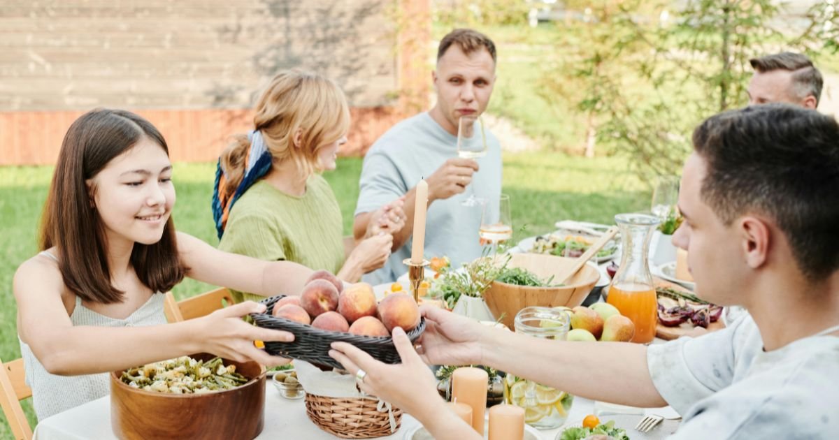 people sitting around table of food outside.
